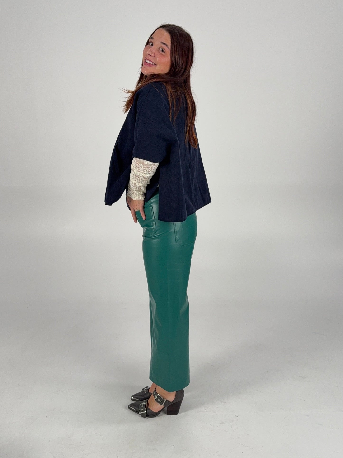 “Green leather pants styled with a navy poncho and white lace long sleeve — elevated holiday boutique outfit.”