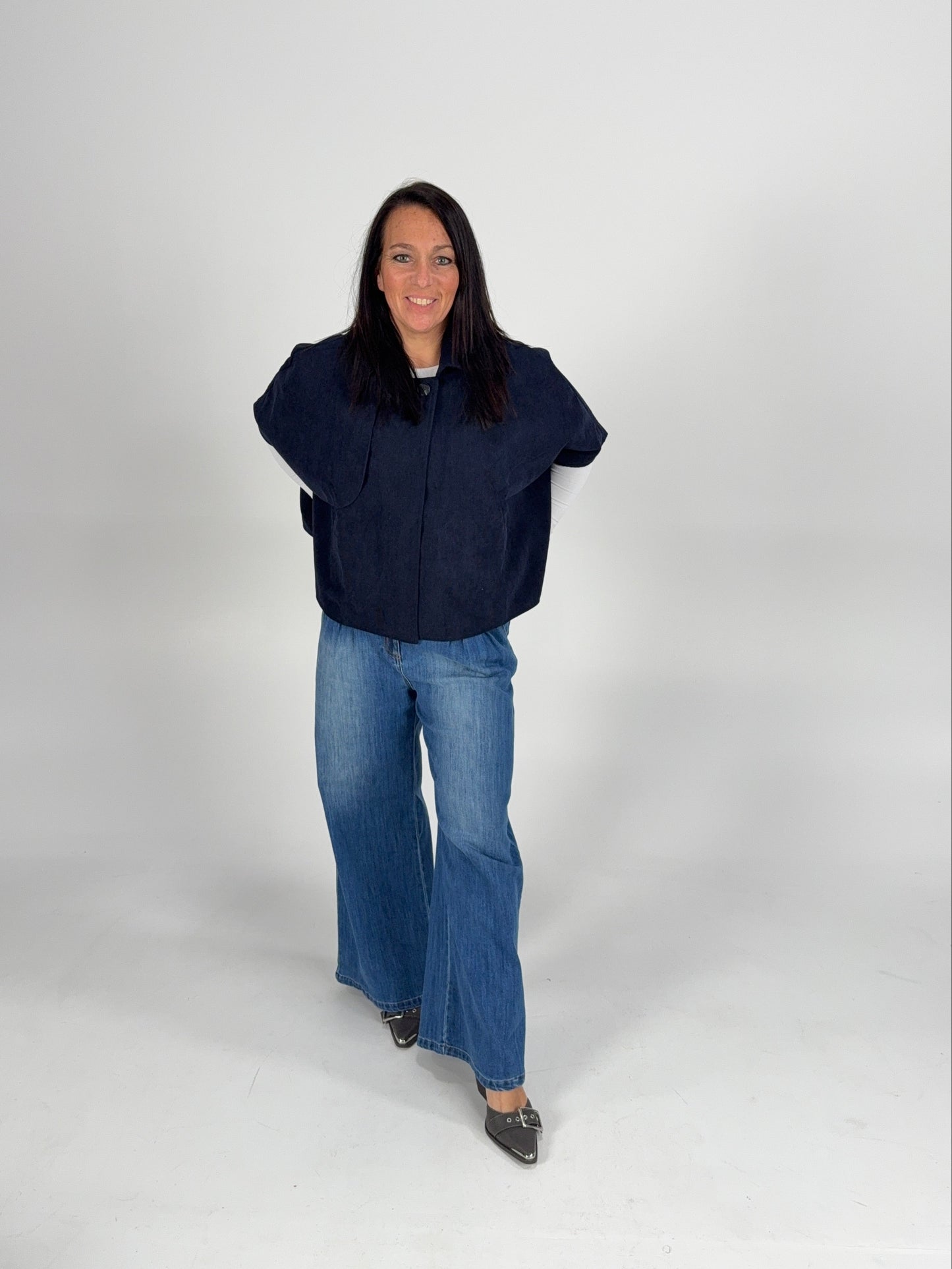“Navy poncho layered over a white lace long sleeve top with denim — cozy casual winter boutique outfit.”