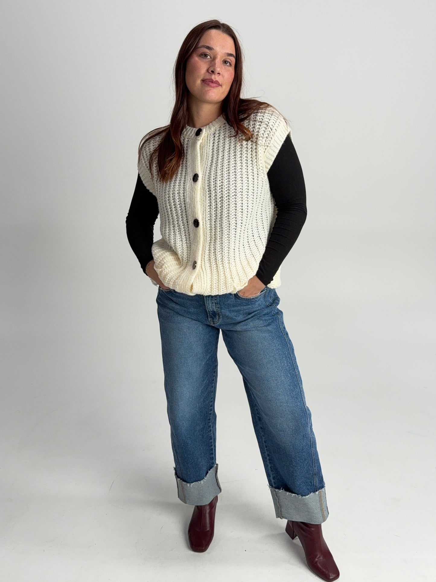 “Chunky knit sweater vest styled over a long sleeve top — cozy layered winter boutique outfit.”