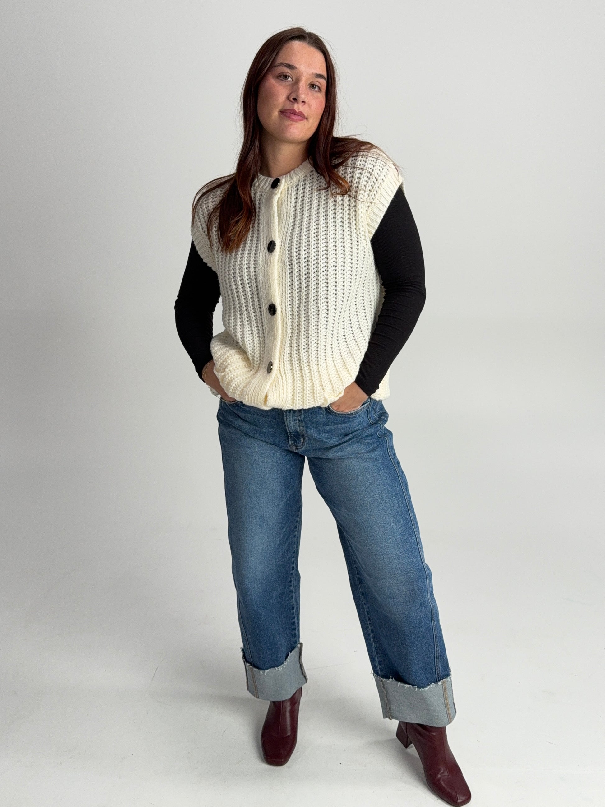 “Chunky knit sweater vest styled over a long sleeve top — cozy layered winter boutique outfit.”